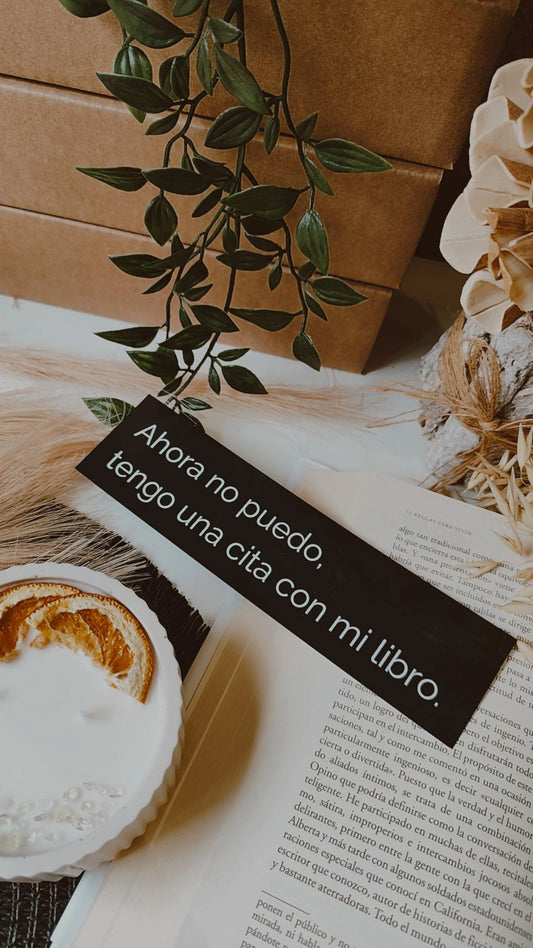 Marcapáginas negro sobre un libro abierto, ideal para amantes de la lectura.